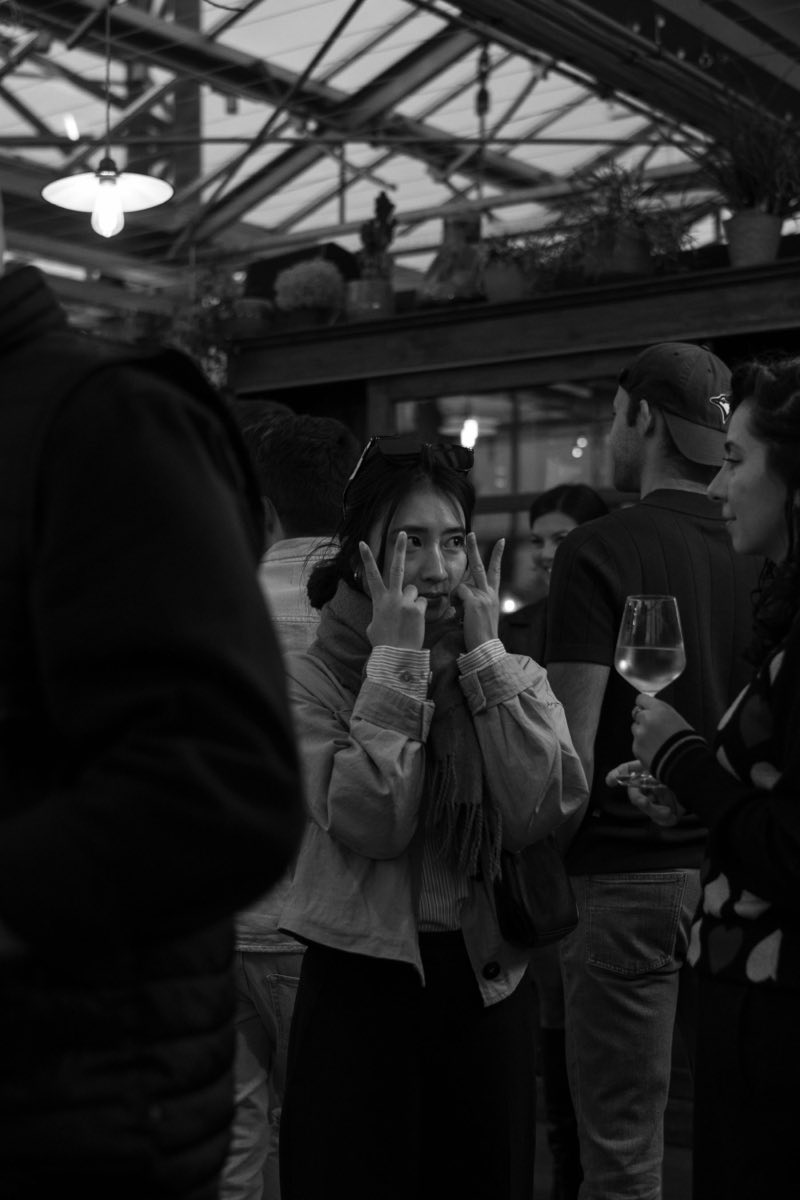 People standing close together talking late in a bar, a glass raised between them