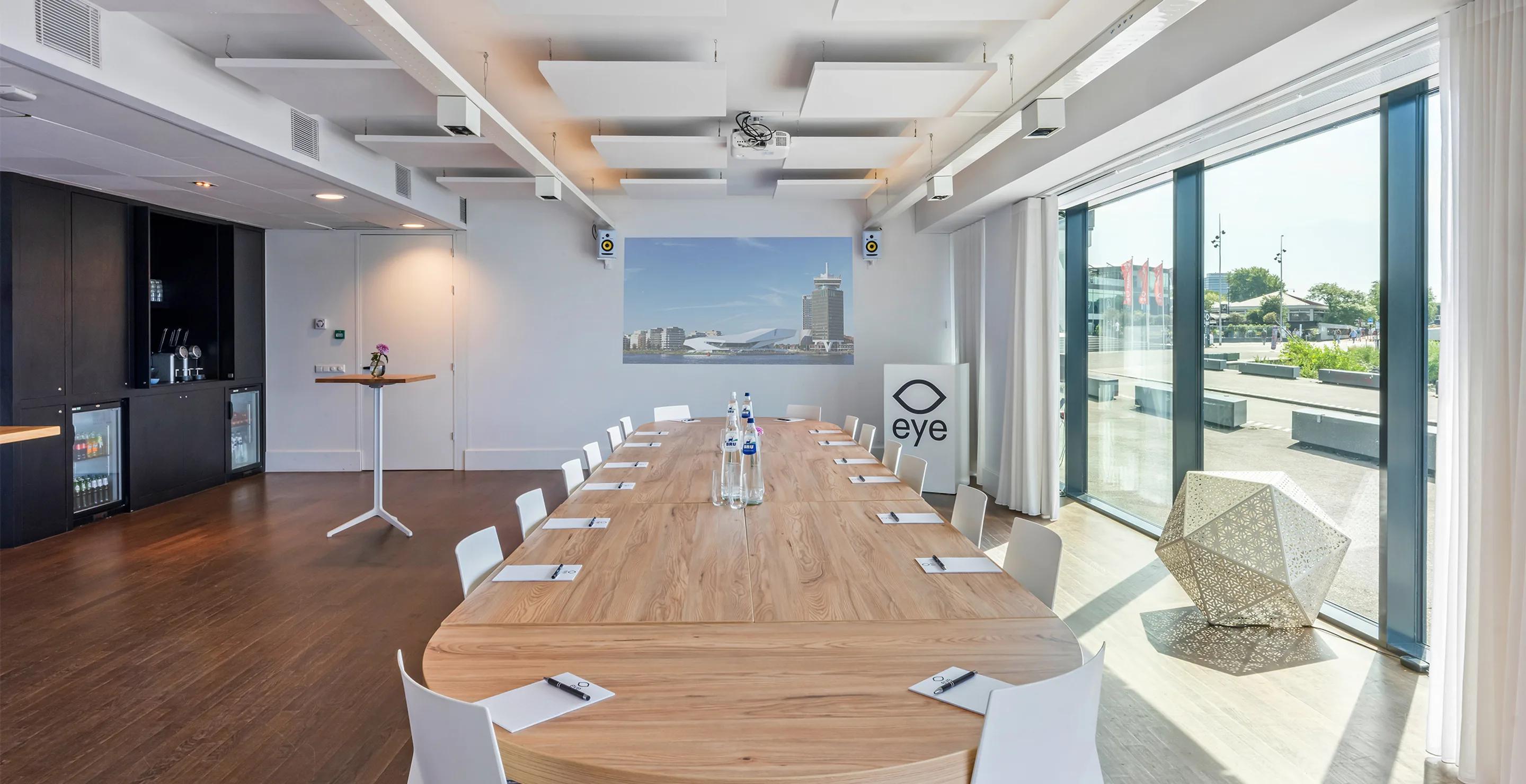 A meeting room inside Eye Filmmuseum set with a long table and chairs, overlooking the waterfront